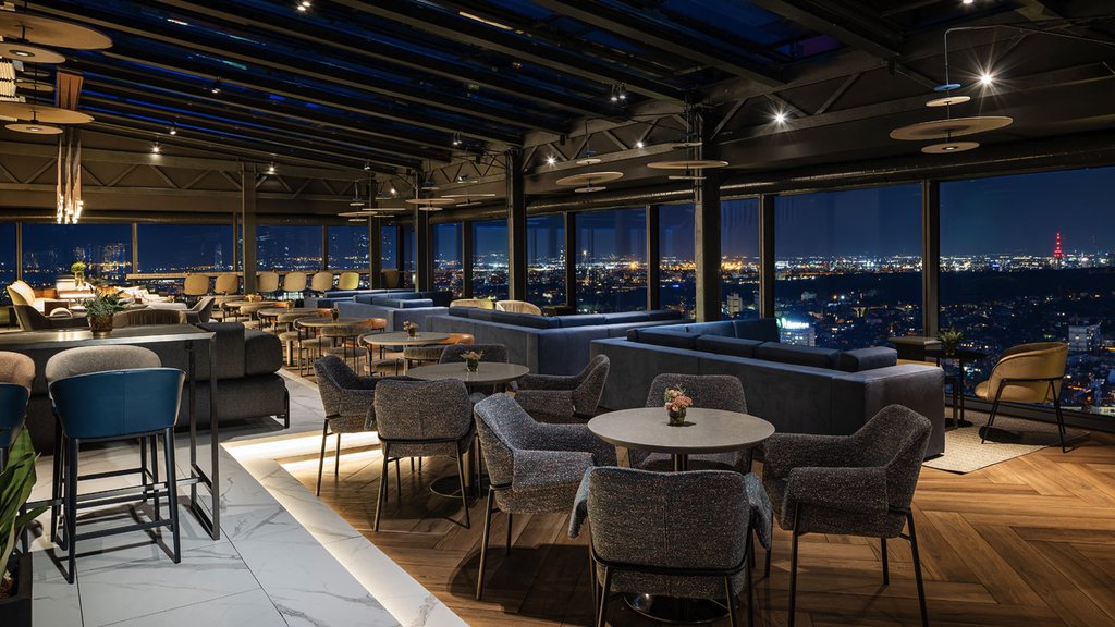 An empty restaurant with windows looking out at a city at night.