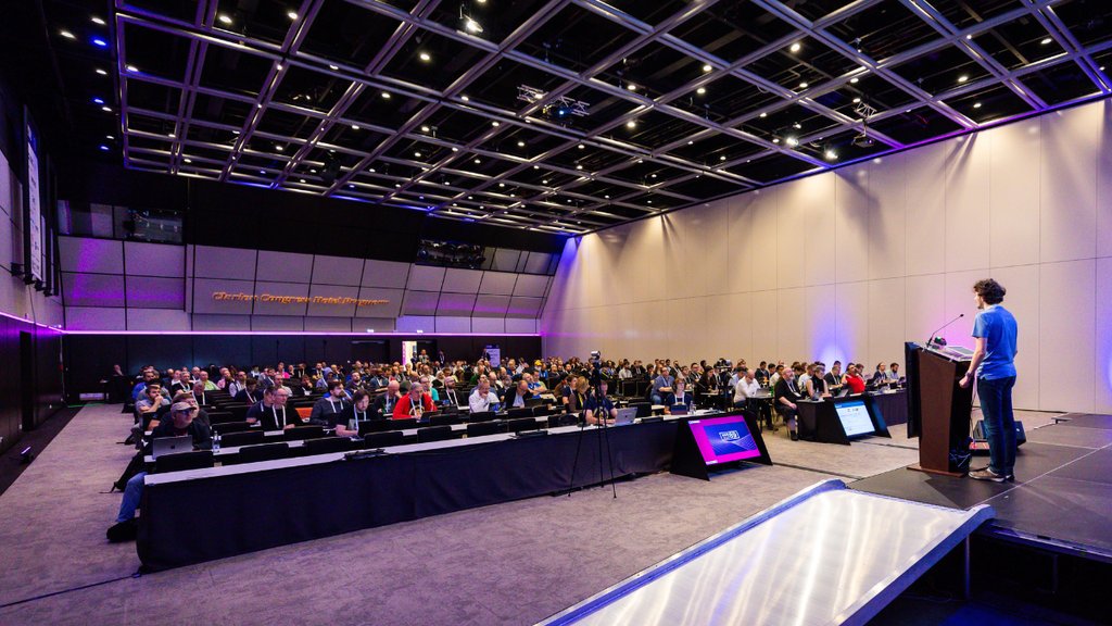 An audience sits at a RIPE Meeting watching a man present.